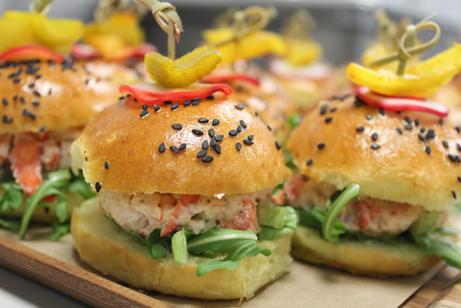Lobster roll sliders with poppy seed buns and pickle garnish