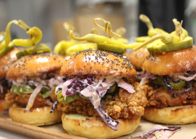 Close up of fried chicken on poppy slider buns with pickle garnish
