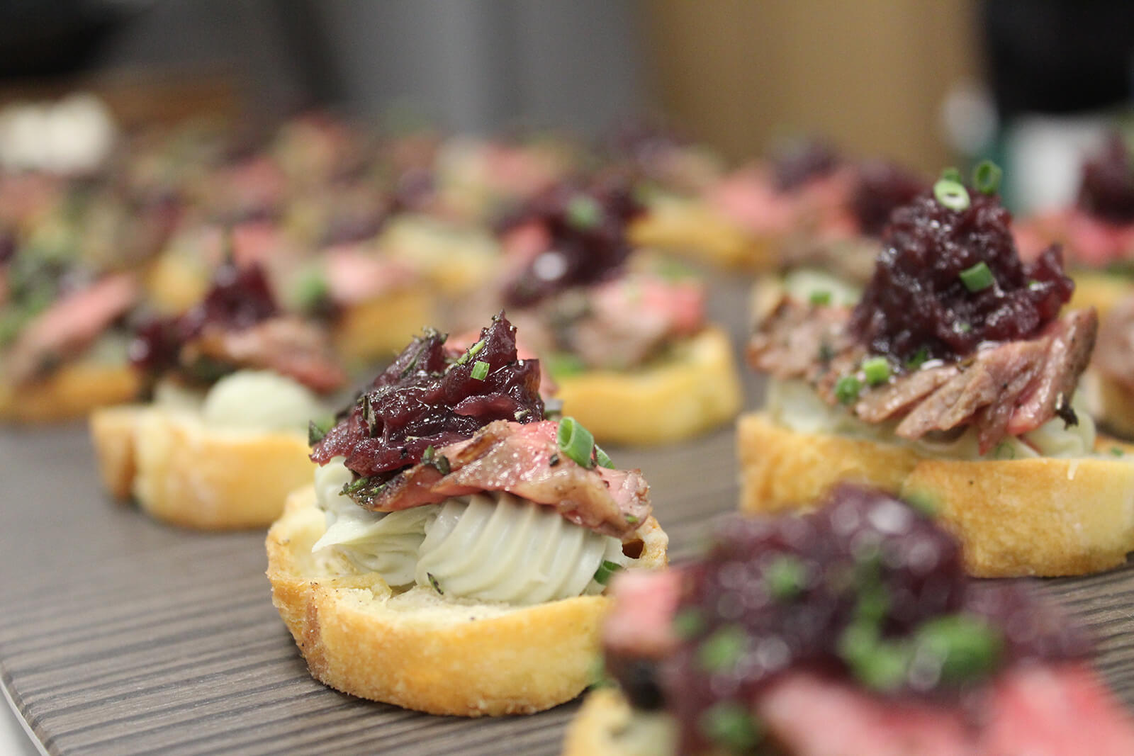 Close up of mini toast rounds topped with meat and fruit chutney